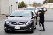 A member of the Hope Ministries Church check-in residents who line up at a drive-through food distribution in South San Francisco, CA, on April 8, 2020.  The food drive was organized to help families in need during the COVID-19 pandemic.