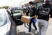 Members of the Hope Ministries Church load a box of food in a car at a drive-through food distribution in South San Francisco, CA, on April 8, 2020.  The food drive was organized to help families in need during the COVID-19 pandemic.