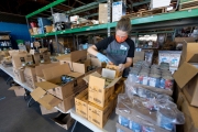 A volunteer loads food into bags at the Alameda Food Bank distribution center in Alameda, CA, on April 15, 2019. The food was distributed later through a drive-through to people in need following the loss of their jobs due to the “shelter-in-place” order to limit the spread of the coronavirus SARS-CoV-2.