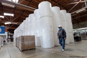 A blind worker walks by 1,000-pound rolls of toilet paper inside the Sirkin Center in San Leandro, CA, on May 11, 2020.