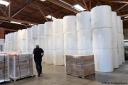 A sighted worker walks by 1,000-pound rolls of toilet paper inside the Sirkin Center in San Leandro, CA, on May 11, 2020.