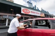 A waiter or carhop brings a meal to a customer waiting in his car at the Mel’s  Drive-In restaurant in San Francisco, CA, on May 12, 2020.Like in the 1950’s, Mel's Drive-In restaurant in San Francisco is now offering carhop service so customers stay safe while still feeling like they get the experience of eating out during the shelter-in-place order due to the coronavirus pandemic.
