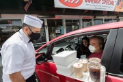 A waiter or carhop brings a meal to  customers waiting in their car at the Mel’s  Drive-In restaurant in San Francisco, CA, on May 12, 2020.Like in the 1950’s, Mel's Drive-In restaurant in San Francisco is now offering carhop service so customers stay safe while still feeling like they get the experience of eating out during the shelter-in-place order due to the coronavirus pandemic.