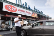A waiter or carhop brings a meal to a customer waiting in his car at the Mel’s  Drive-In restaurant in San Francisco, CA, on May 12, 2020.Like in the 1950’s, Mel's Drive-In restaurant in San Francisco is now offering carhop service so customers stay safe while still feeling like they get the experience of eating out during the shelter-in-place order due to the coronavirus pandemic.