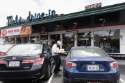 A waiter or carhop brings a meal to a customer waiting in his car at the Mel’s  Drive-In restaurant in San Francisco, CA, on May 12, 2020.Like in the 1950’s, Mel's Drive-In restaurant in San Francisco is now offering carhop service so customers stay safe while still feeling like they get the experience of eating out during the shelter-in-place order due to the coronavirus pandemic.