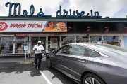 A waiter or carhop brings a meal to a customer waiting in his car at the Mel’s  Drive-In restaurant in San Francisco, CA, on May 12, 2020.Like in the 1950’s, Mel's Drive-In restaurant in San Francisco is now offering carhop service so customers stay safe while still feeling like they get the experience of eating out during the shelter-in-place order due to the coronavirus pandemic.