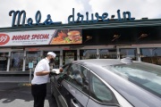 A waiter or carhop brings a meal to a customer waiting in his car at the Mel’s  Drive-In restaurant in San Francisco, CA, on May 12, 2020.Like in the 1950’s, Mel's Drive-In restaurant in San Francisco is now offering carhop service so customers stay safe while still feeling like they get the experience of eating out during the shelter-in-place order due to the coronavirus pandemic.