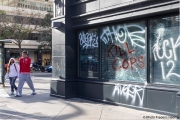 A couple  walks by a local store in Oakland, CA, on May 30, 2020,, that had its storefront smashed and filled with graffitti.