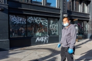 A store owner stands in front of his  store in Oakland, CA, on May 30, 2020,, that had its storefront smashed and filled with graffitti.