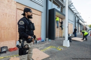 A private security guard stands in front of the Mercedes-Benz dealership   in Oakland, CA, on May 30, 2020 with workers boarding up the storefront that was smashed during violent  protests the night before.